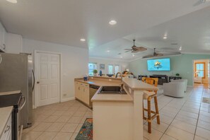 A modern kitchen with a central island, a refrigerator, and a dining area with a television. - Sleeps 8 - 2 bath- Pool and Hot Tub - Pet Friendly (Cape Coral)