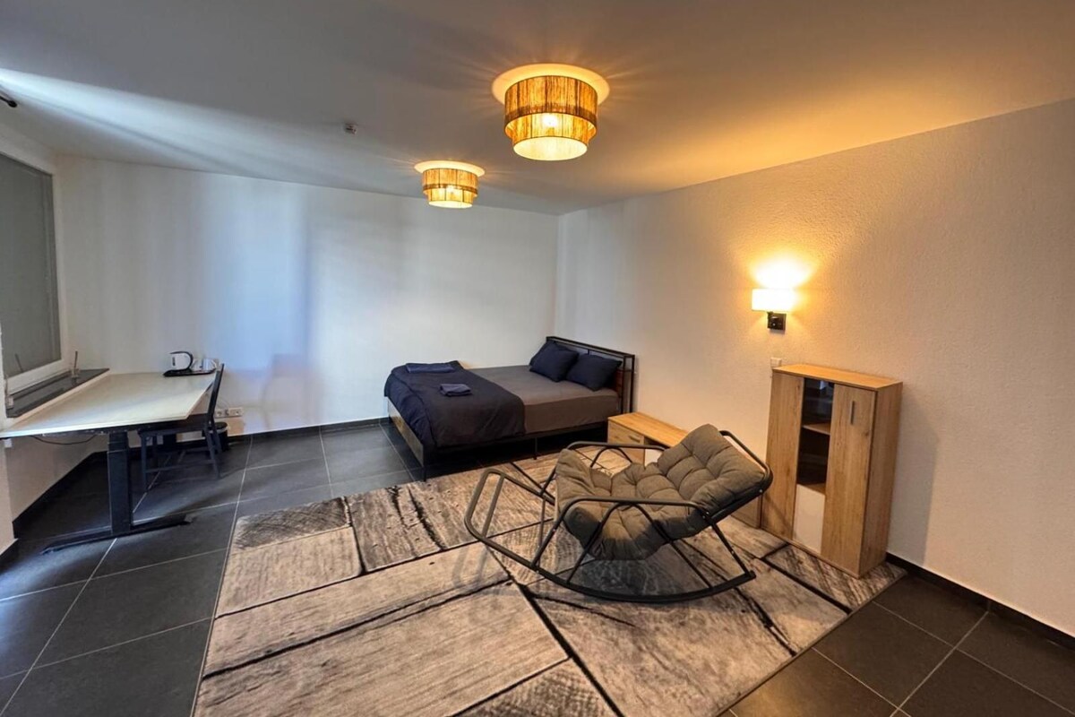 Una habitación moderna con una cama, un escritorio, una silla y una lámpara.