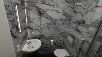 Ein Badezimmer mit einem weißen Waschbecken, einer Toilette und einer Duschkabine.