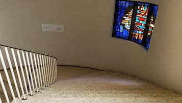 A staircase with a white railing and a stained glass window on the wall.