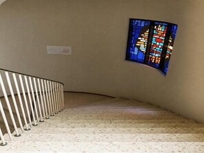 Una escalera con barandilla blanca y un ventanal de vitral en la pared.