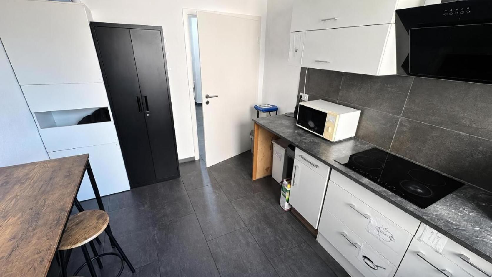 A modern kitchen with a microwave, stove, and white cabinets.
