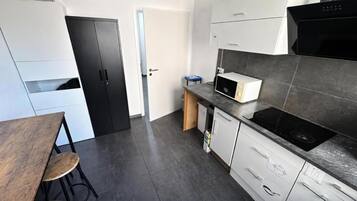 A modern kitchen with a microwave, stove, and white cabinets.
