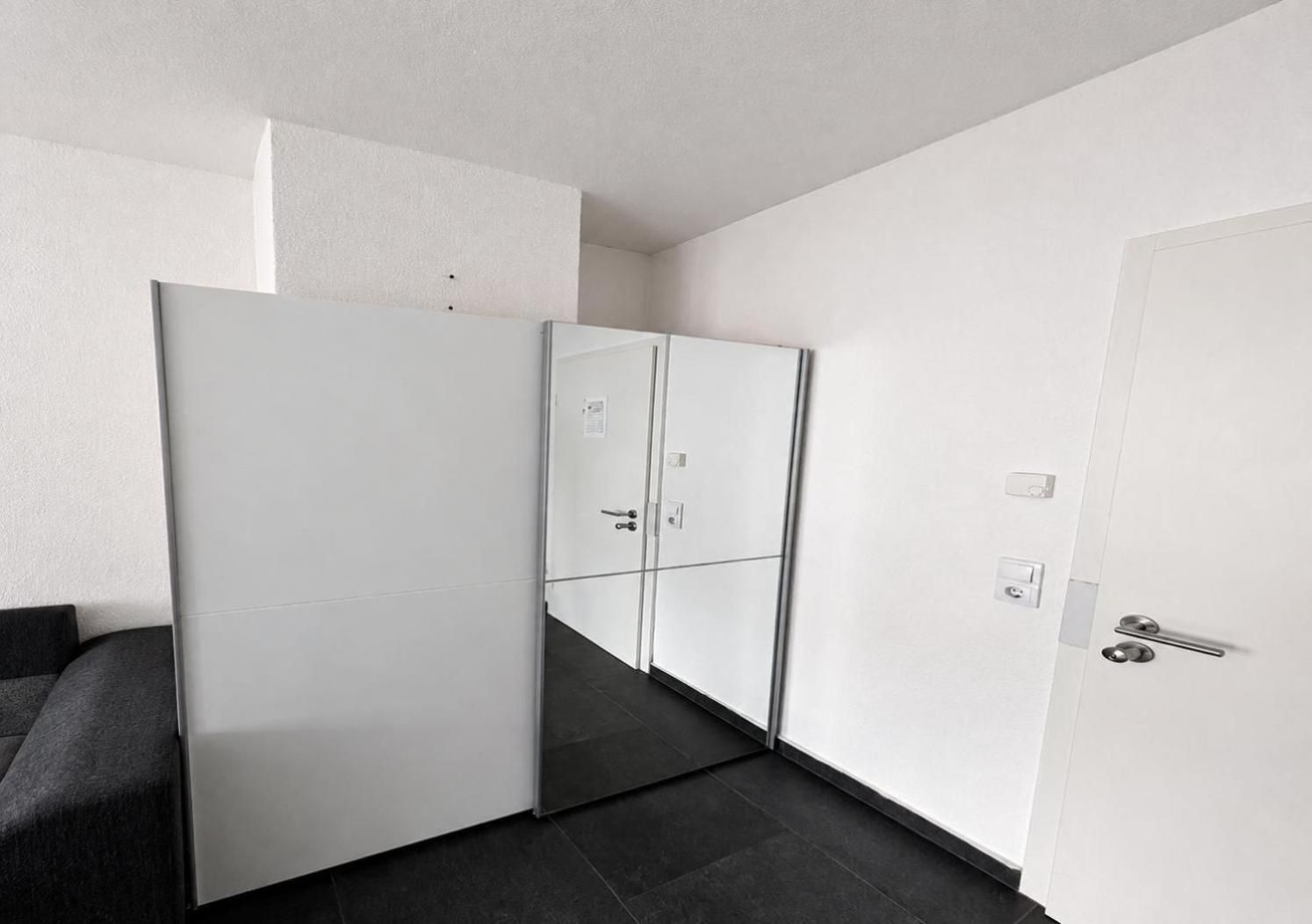 Een moderne kamer met een grote kledingkast, een deur en een donkere vloer.