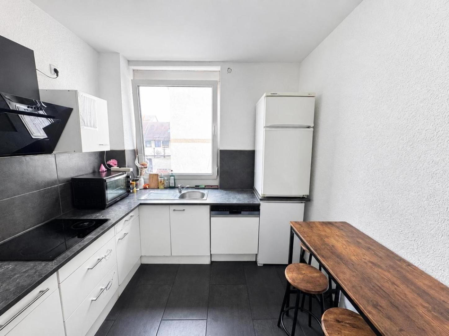 Eine kompakte Küche mit Einbauherd, Spüle und Kühlschrank.