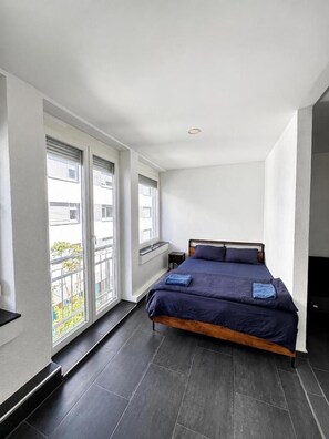 Un dormitorio con cama, ventana y vistas al exterior.