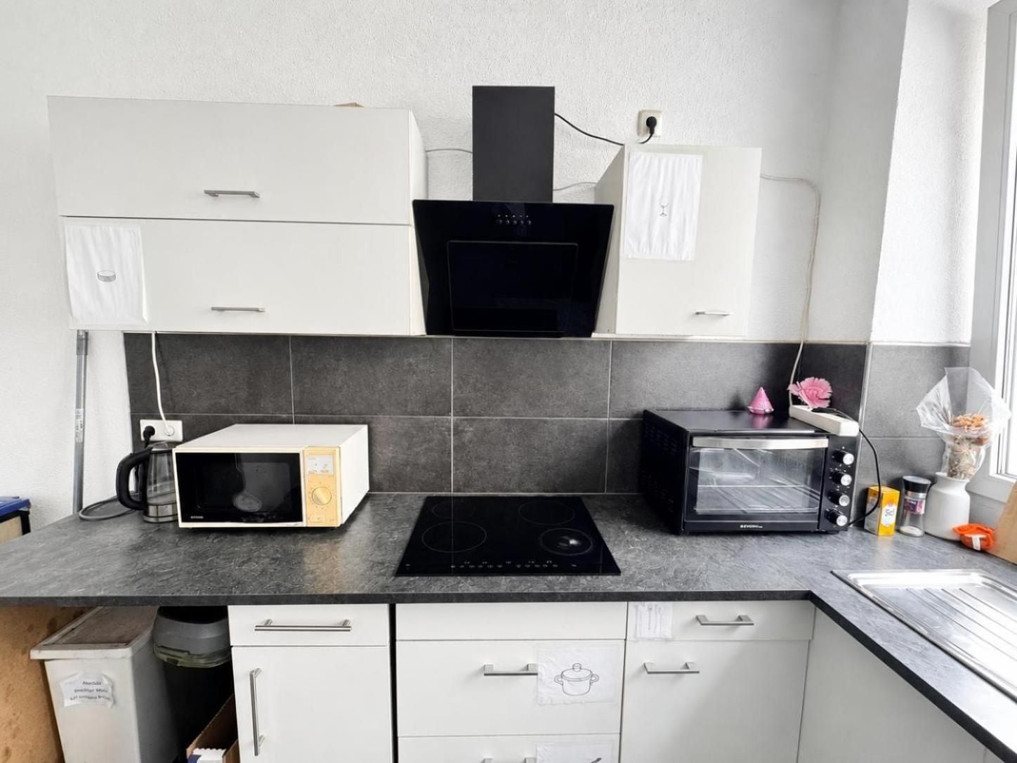A kitchen with white cabinets, a black microwave, a toaster, and a stove.