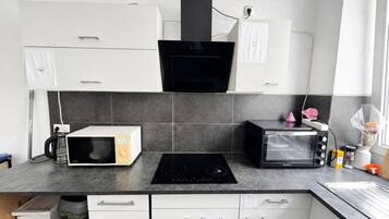 A kitchen with white cabinets, a black microwave, a toaster, and a stove.