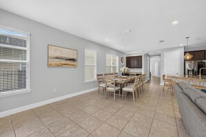 A spacious kitchen with modern appliances, a dining area with a large table and chairs, and a living area with a sofa and a coffee table. - 5BR Encore Sleeps 12 w/ Pool, Spa & Game Tables (Kissimmee)