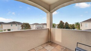 Ein Balkon mit Blick auf angrenzende Häuser und einen klaren Himmel.