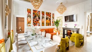 A dining area with a long table set for a meal, a sofa, and a television mounted on the wall. - Spectacular 6 bedroom in the Heart of the Opéra District (Paris)