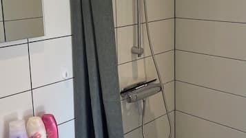 Un baño con ducha, lavamanos y artículos de aseo.