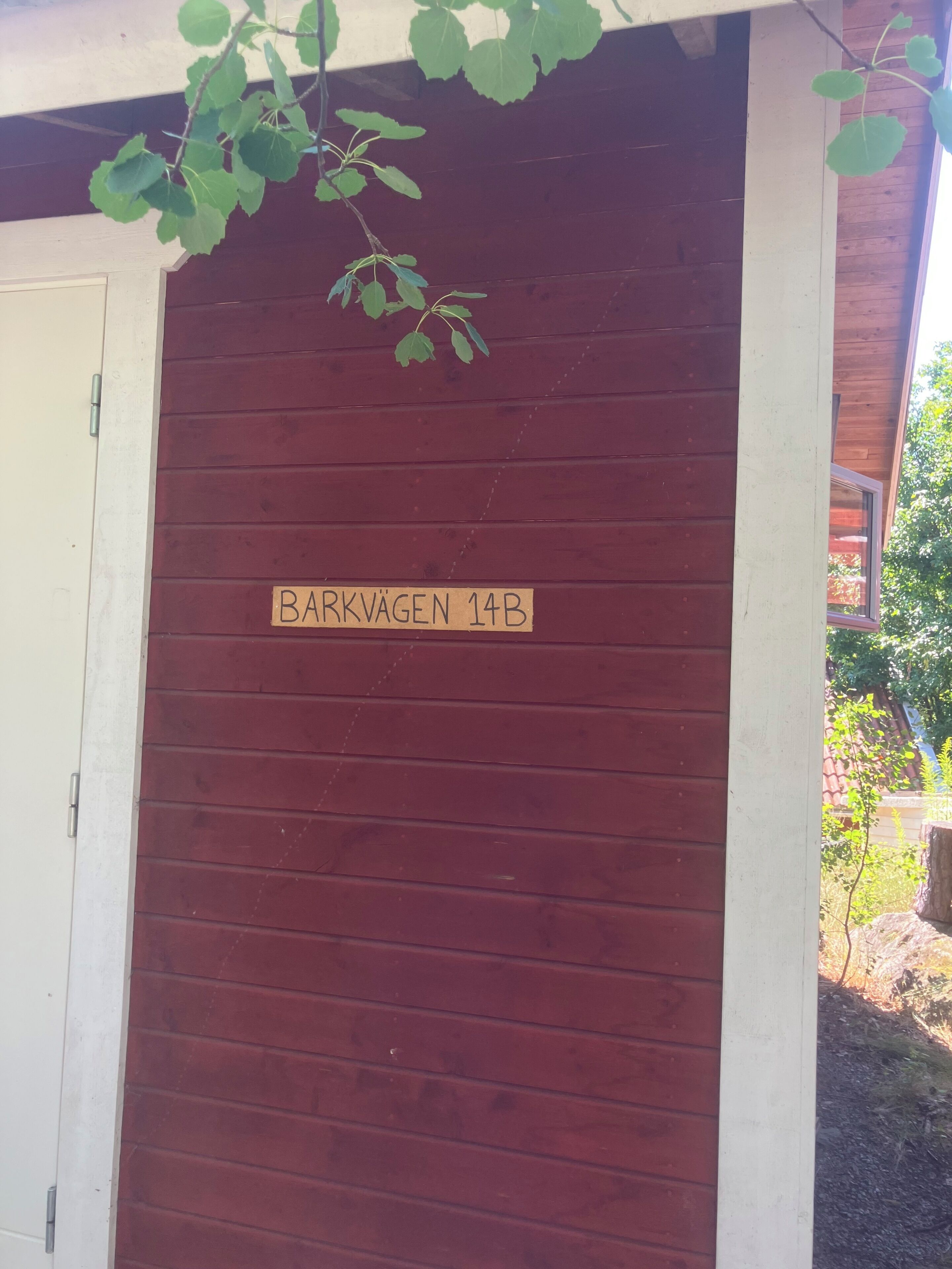 Uma porta de madeira com uma placa que diz 'BARKVAGEN 14B'.