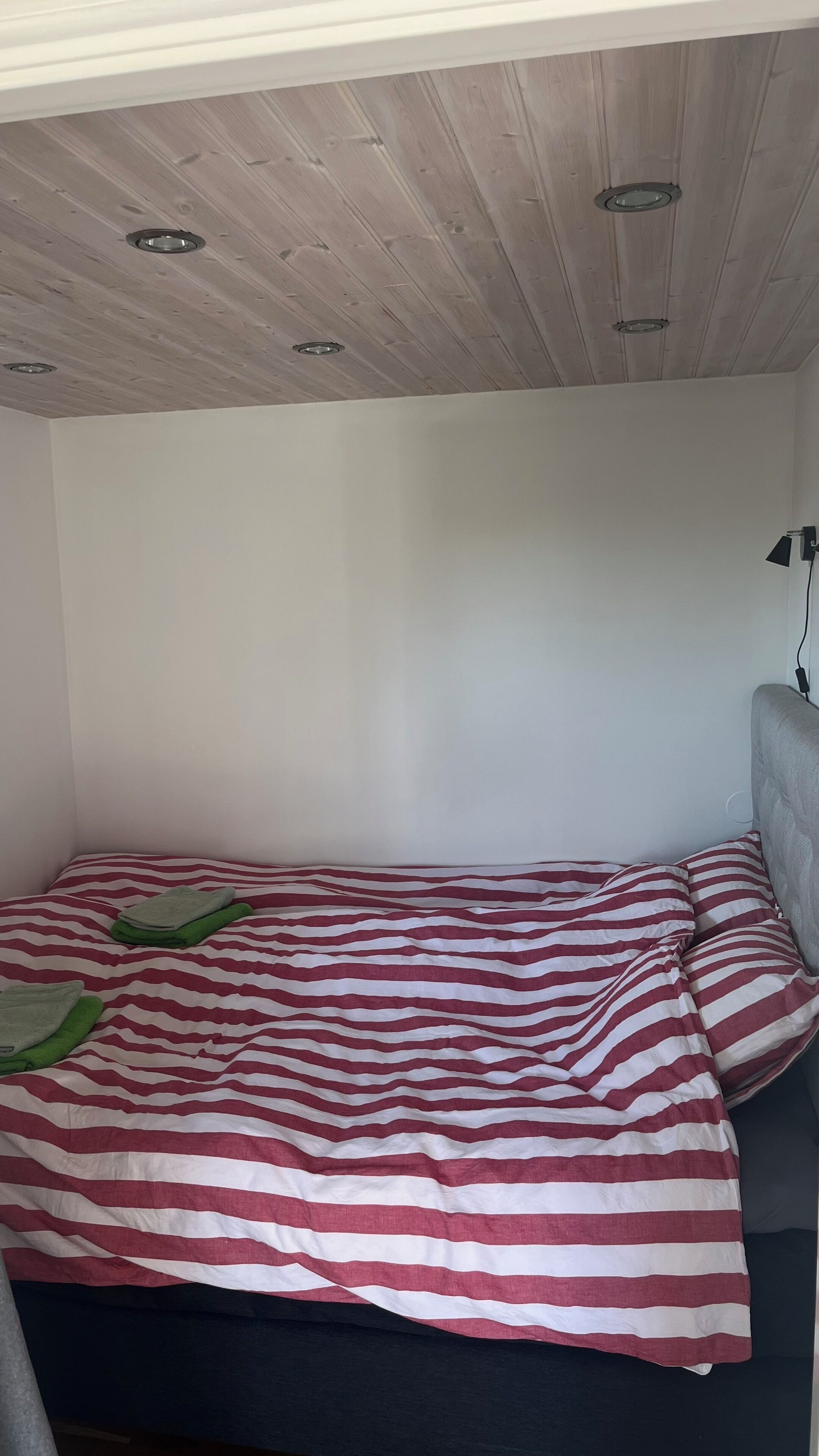 Quarto com cama, cabeceira e iluminação embutida no teto.