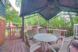 A covered outdoor patio with a round table and chairs, surrounded by a wooden deck and a metal railing. - Historic Cleveland Hideaway Near Downtown! (Cleveland)