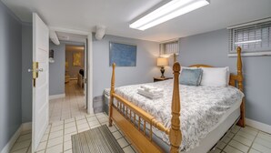 A bedroom with a four-poster bed, a nightstand with a lamp, and a window with blinds. - Historic Cleveland Hideaway Near Downtown! (Cleveland)