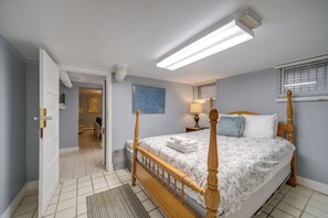 A bedroom with a four-poster bed, a nightstand with a lamp, and a window with blinds. - Historic Cleveland Hideaway Near Downtown! (Cleveland)