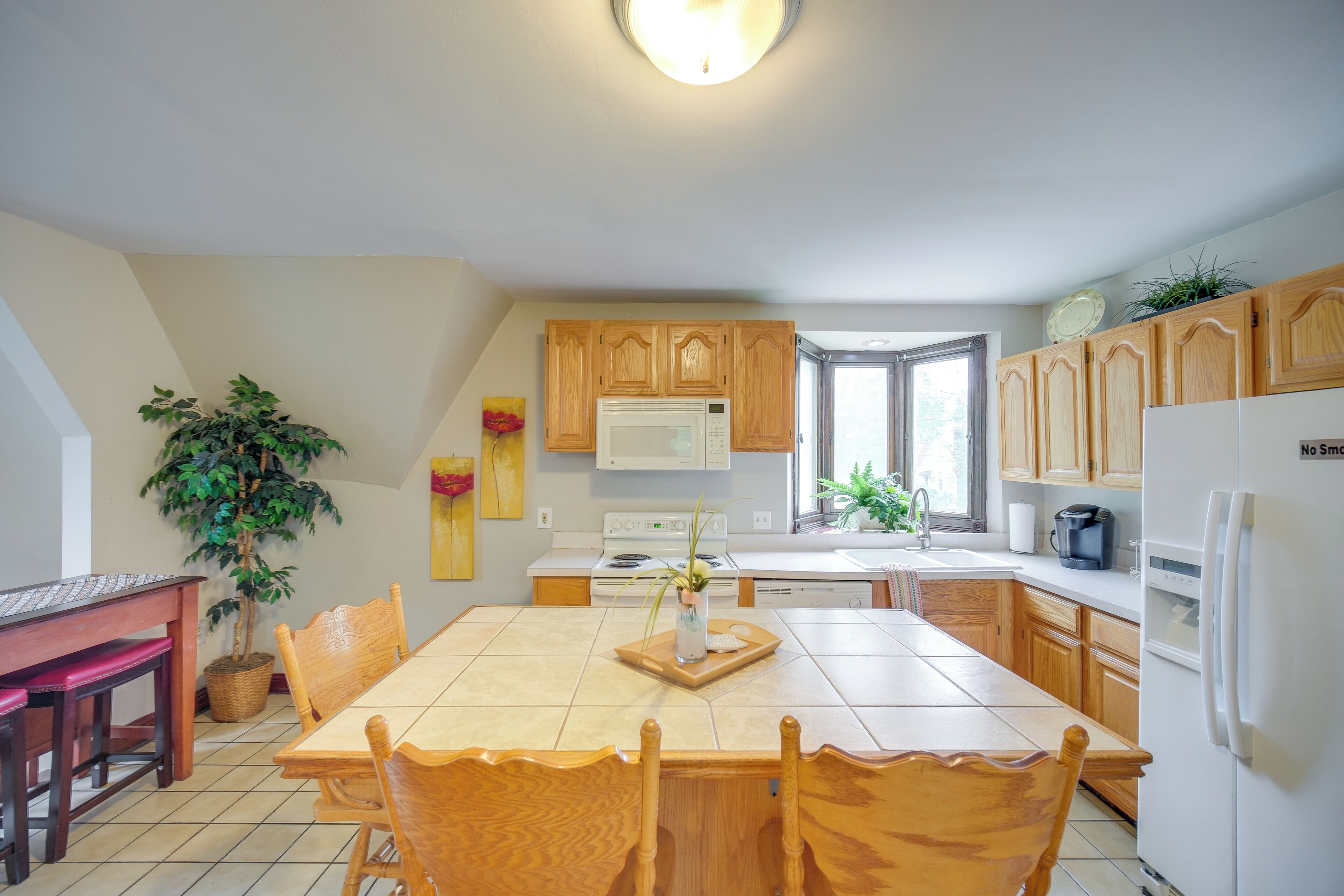 Une cuisine avec des meubles de rangement en bois, une table à manger avec des chaises, une cuisinière et un réfrigérateur.
