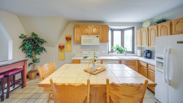 A kitchen with wooden cabinets, a dining table with chairs, a stove, and a refrigerator. - 6 Mi to Dtwn! Historic Haven in Cleveland (Cleveland)