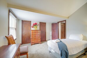 Ein Schlafzimmer mit einem Bett, einem Holzschrank, einem Stuhl und einem Fenster mit Jalousien.
