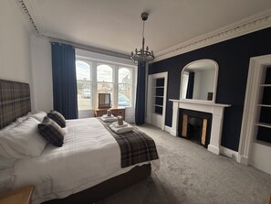 A hotel room with a large bed, a fireplace, a mirror, and a view of the outside. - No. 48 | Highland Castle View | Inverness City Centre | Free Parking | Sleeps 8 (Inverness)