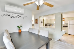 A modern kitchen with white cabinets, a microwave, and a refrigerator. There is a dining area with a table and chairs. - Walk to Dtwn Clayton & River! 2-unit Getaway (Clayton)