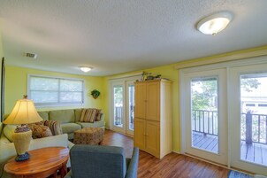 A room with a sofa, a table, a cabinet, and a window with blinds.