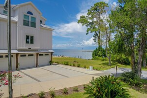 A two-story house with a garage, a paved driveway, and a view of the sea.