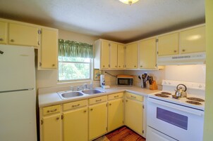 A kitchen with yellow cabinets, a refrigerator, a microwave, and a stove.