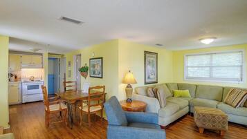A living room with a dining area, a kitchen, and a blue door leading to another room.