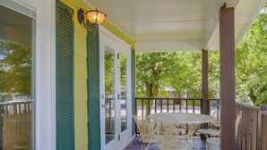 A covered porch with a table and chairs, a door with a window, and a railing. - Walk to Beach! Water-view Fairhope Retreat (Fairhope)