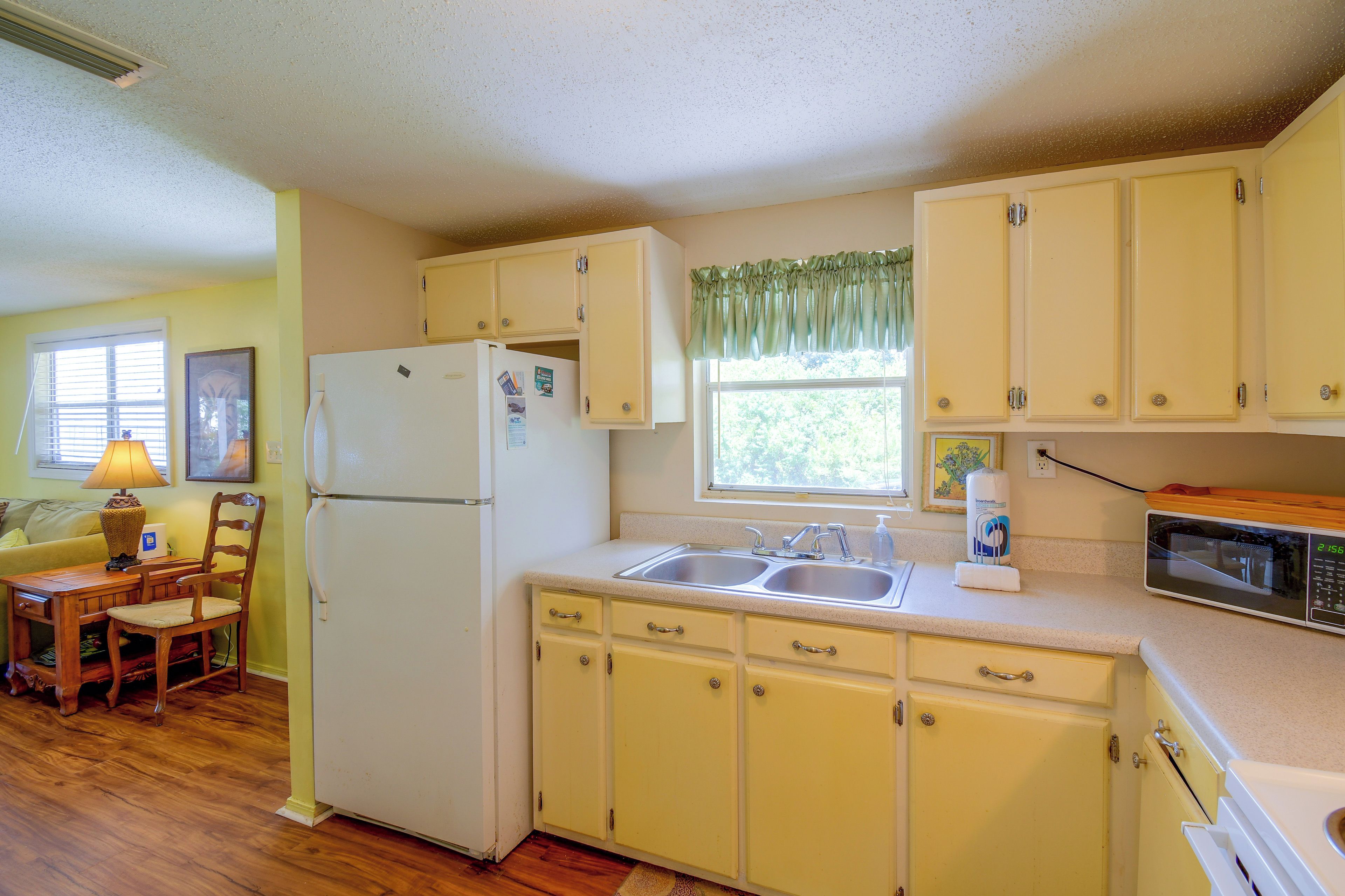 A compact kitchen with a refrigerator, double sink, and a microwave.