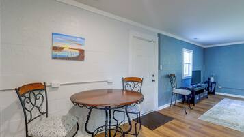 A dining area with a round table and four chairs, a painting on the wall, and a blue accent wall.