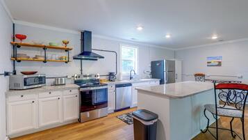 A modern kitchen with white cabinetry, stainless steel appliances, and a central island.