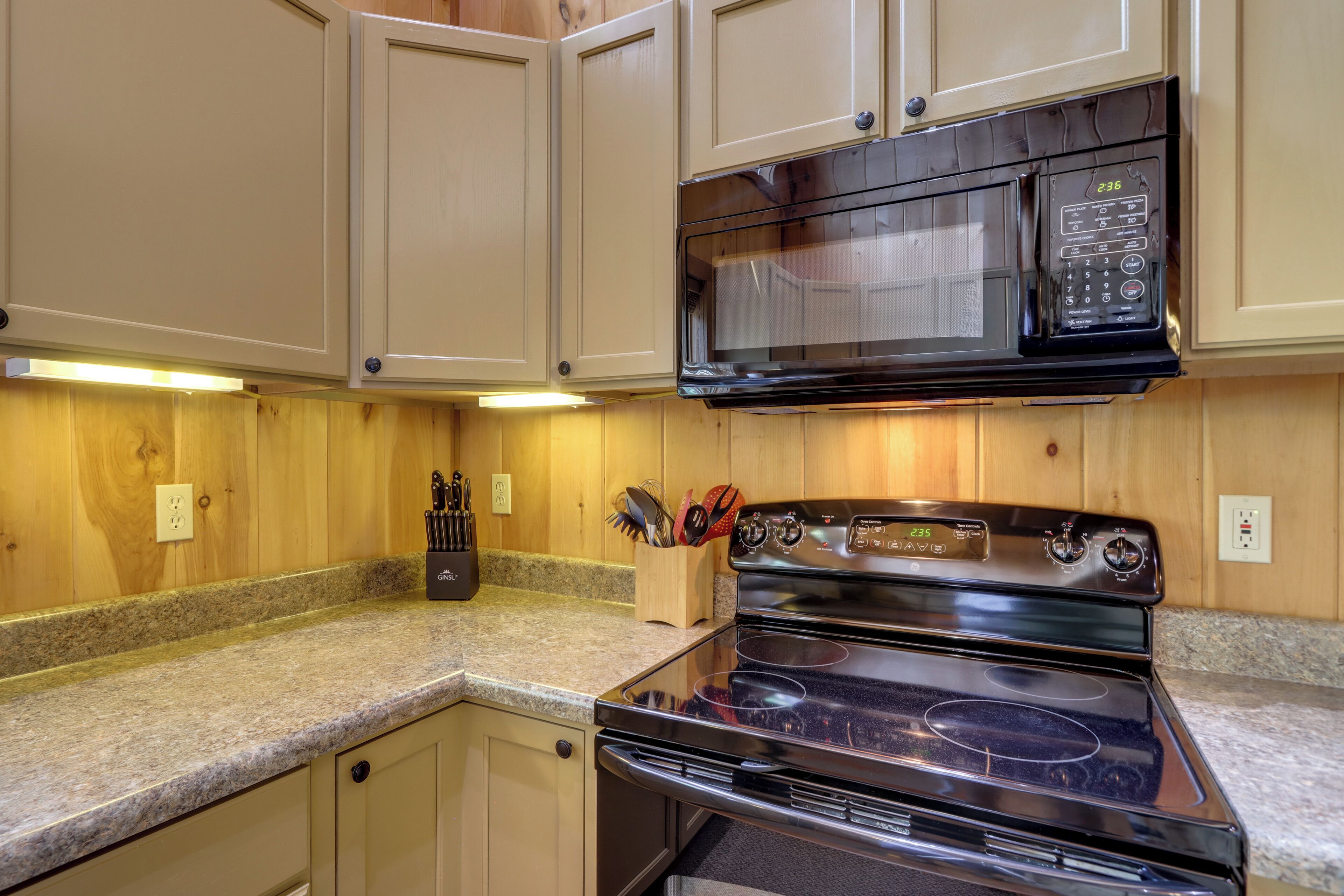 Una cocina con armarios de madera, un microondas negro y una estufa.