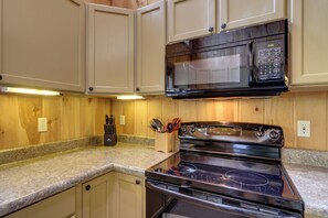Una cocina con armarios de madera, un microondas negro y una estufa.