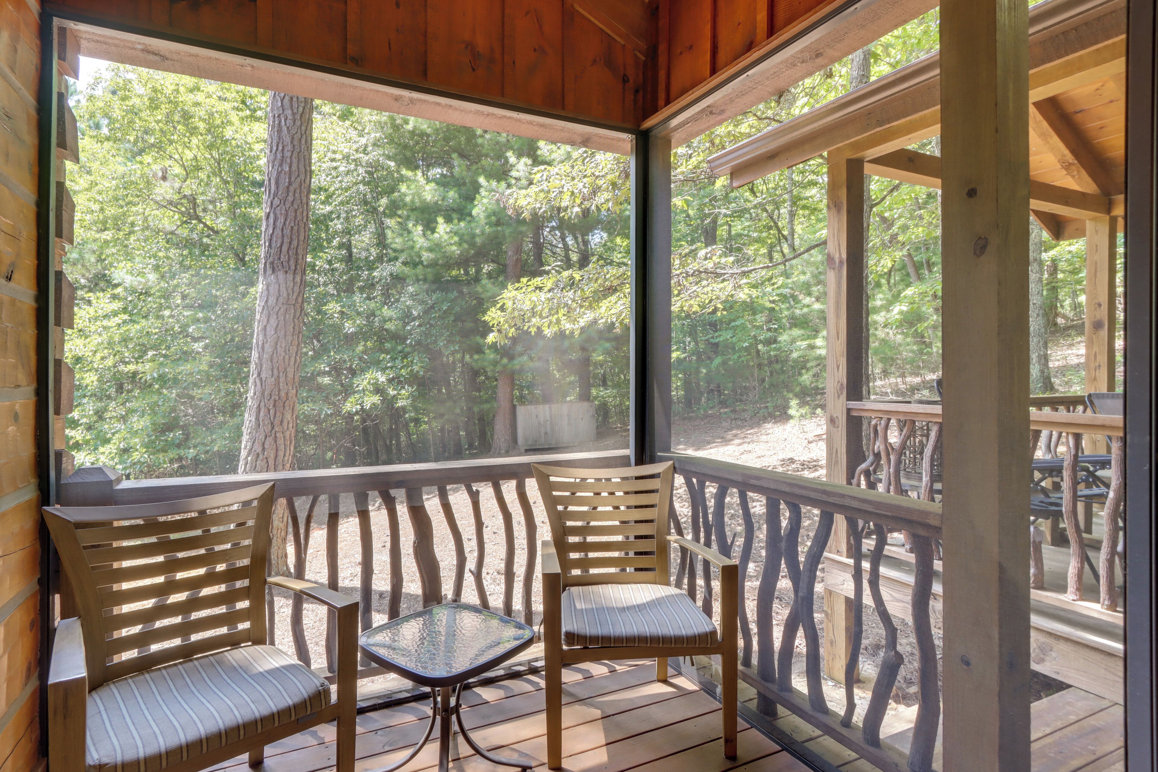 Une terrasse en bois avec deux chaises et une table, donnant sur une zone boisée.