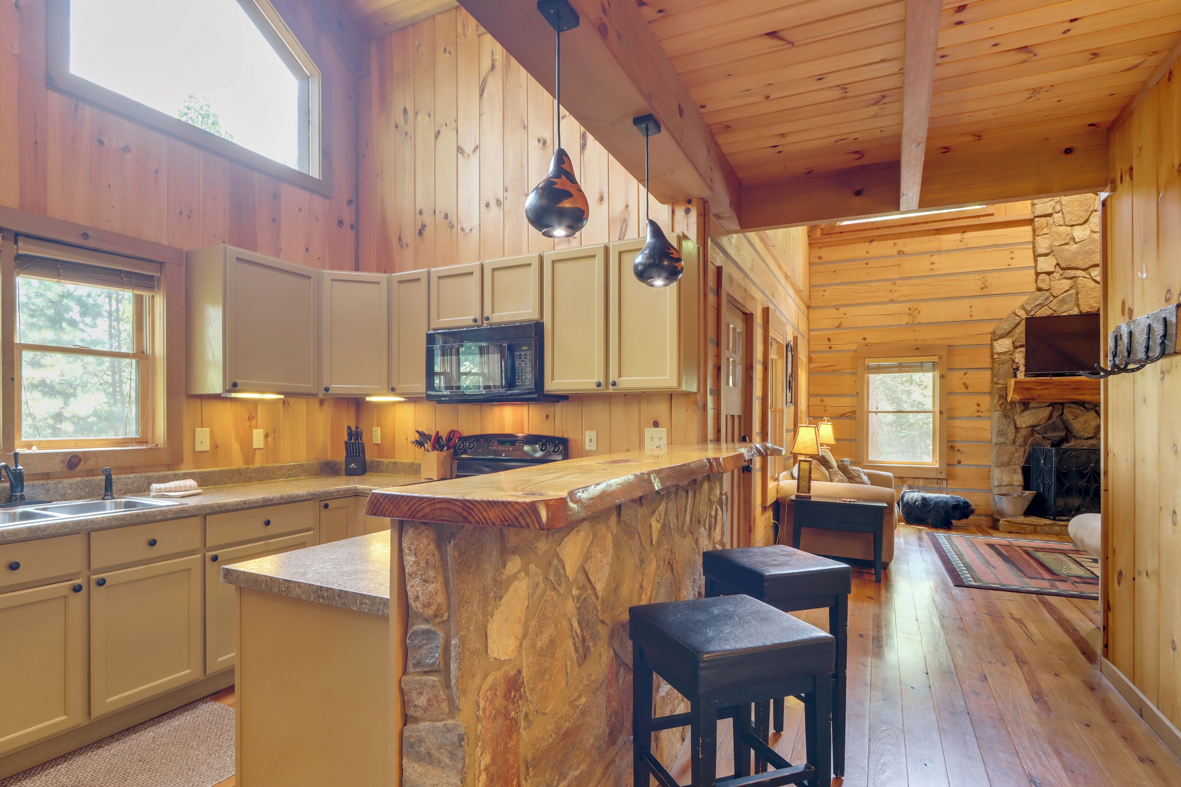L’intérieur d’une cabane comprend une cuisine, un coin repas et une cheminée en pierre.