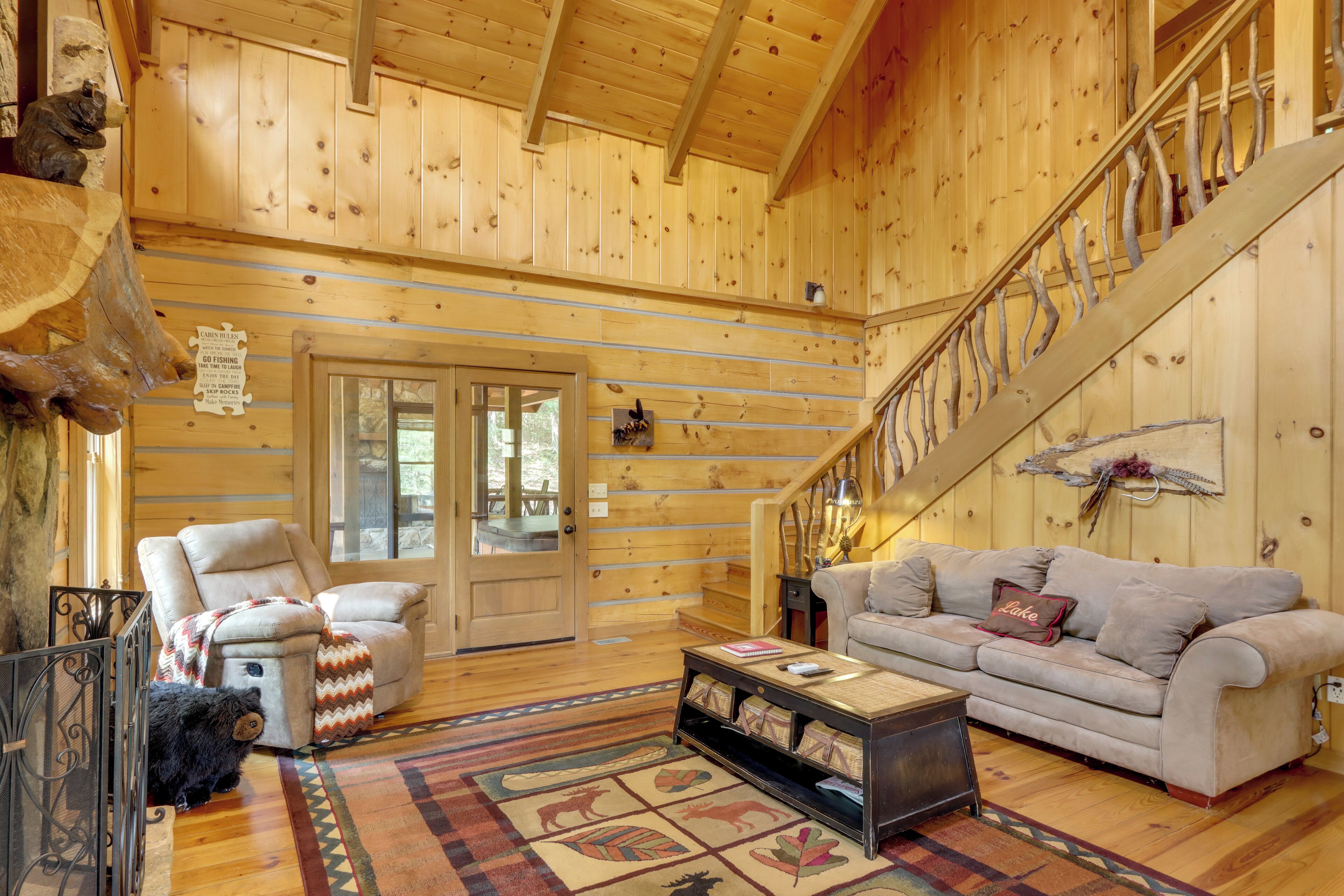 L’intérieur d’un chalet en bois, avec un canapé, un fauteuil et un escalier.
