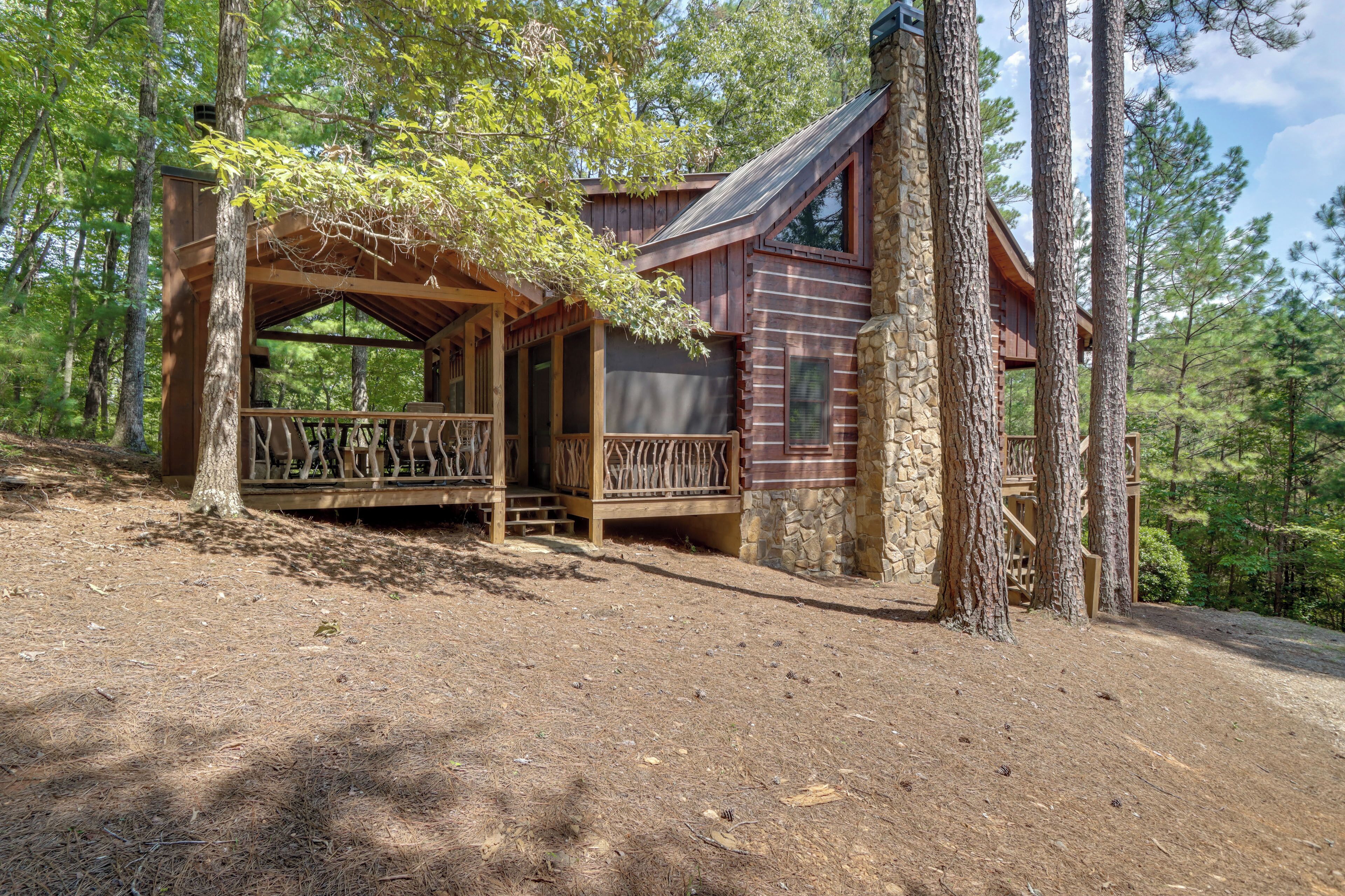 Eine Holzhütte mit einer Holzterrasse, Steinwänden und einer Lage im Wald.