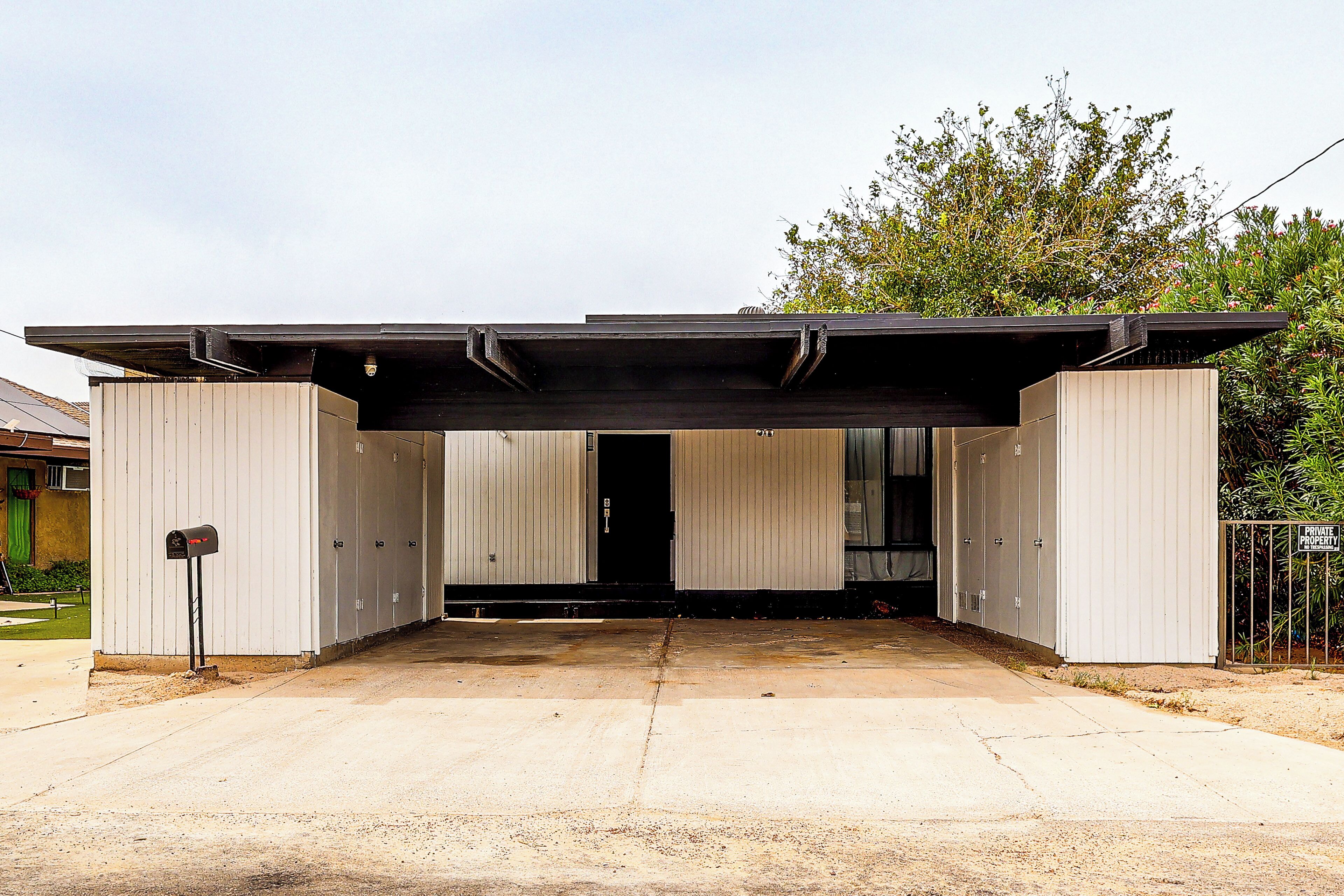 A modern building with a covered entrance, a mailbox, and a gated area.