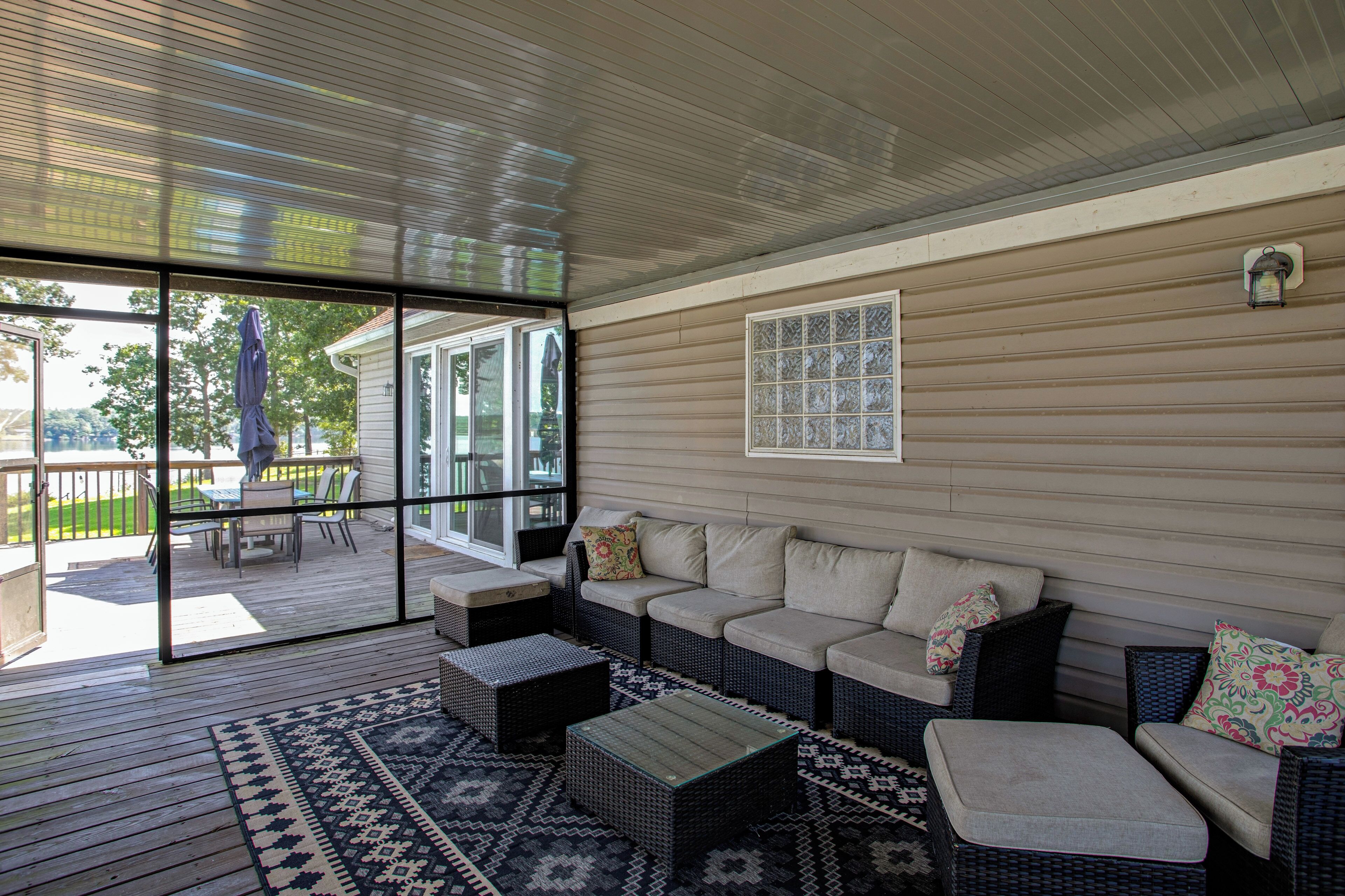 A covered outdoor seating area with a sofa, chairs, and a table.