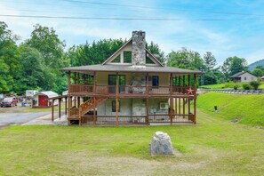 A two-story wooden cabin with a stone chimney, a balcony, and a star decoration. - Creekside Maggie Valley Home w/ Mtn-view Creek-vi (Waynesville)