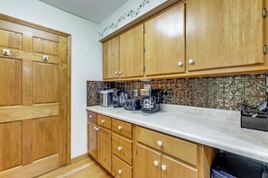 A kitchen with wooden cabinets, a countertop with appliances, and a decorative backsplash. - Creekside Maggie Valley Home w/ Mtn-view Creek-vi (Waynesville)