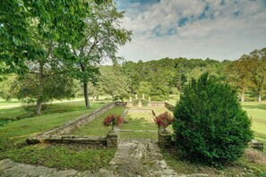 A landscaped garden with stone pathways, a central fountain, and a variety of trees.