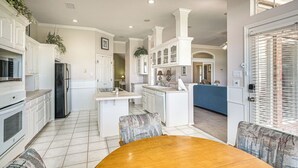 A spacious kitchen with white cabinetry, a central island, and a dining area with a wooden table and patterned chairs.