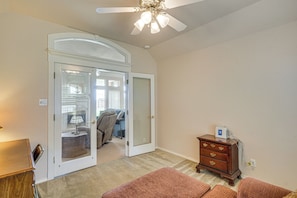 A room with a ceiling fan, a wooden dresser, a door leading to another room, and a carpeted floor. - Spacious Backyard & Patio! Family Haven in Odessa (Odessa)