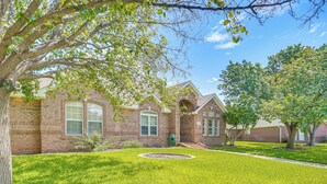 A brick house with a well-maintained lawn and a circular garden bed.