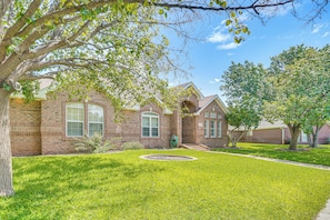 A brick house with a well-maintained lawn and a circular garden bed.