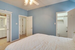 Une chambre à coucher avec un grand lit, une armoire et une porte donnant sur une autre pièce.